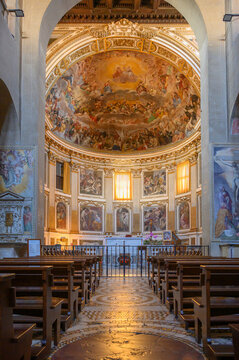 Interior of the Basilica of Santi Quattro Coronati in Rome, Italy, featuring wooden pews and the majestic apse fresco of the Glory of Paradise
