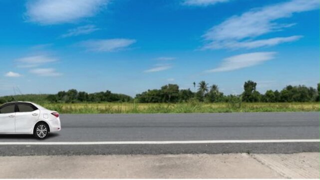 White sedan driving on asphalt road with green landscape 