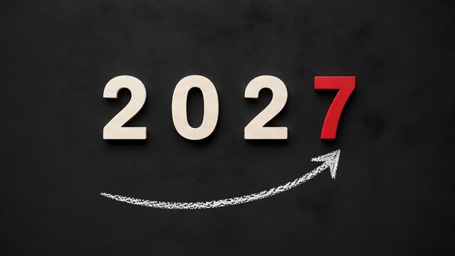 Business growth forecast for 2027 displaying upward pointing chalk arrow and wooden numbers on dark slate representing financial progress