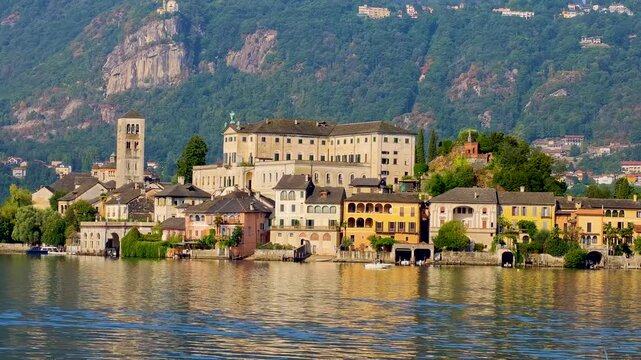 4K video footage of San Giulio Island on Lake Orta during a golden hour and sunset, Piedmont, Italy, featuring the historic basilica and picturesque lakeside scenery surrounded by Alpine landscapes