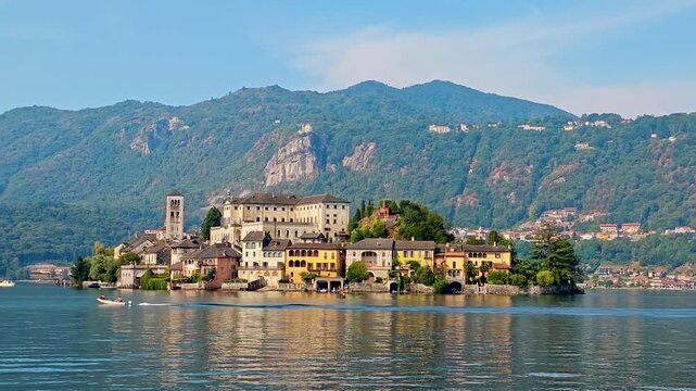 4K video footage of San Giulio Island on Lake Orta during a golden hour and sunset, Piedmont, Italy, featuring the historic basilica and picturesque lakeside scenery surrounded by Alpine landscapes