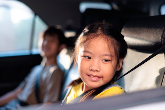 A young girl smiling in the backseat of a car.