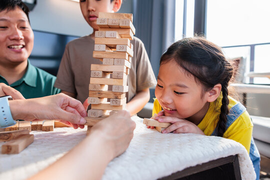 A family enjoys playing a wooden block stacking game