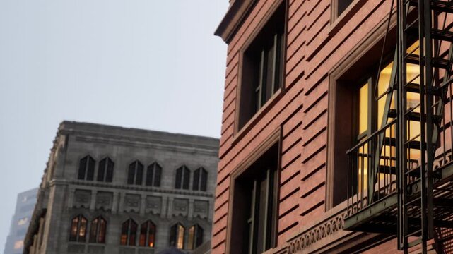 Two buildings are visible in an urban area during twilight. One is a modern structure with large windows, while the other has a historic look with multiple designs.