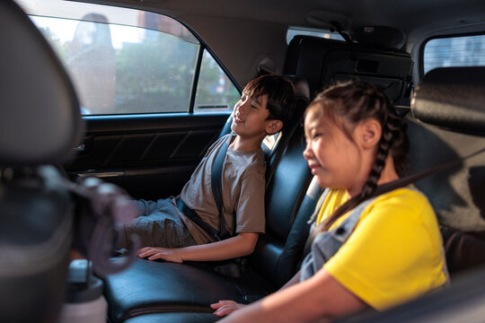 Two children sitting in the back seat of a car.