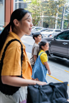 A woman walks outdoors with two young children.