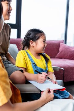 A girl writes in a notebook with adult guidance.