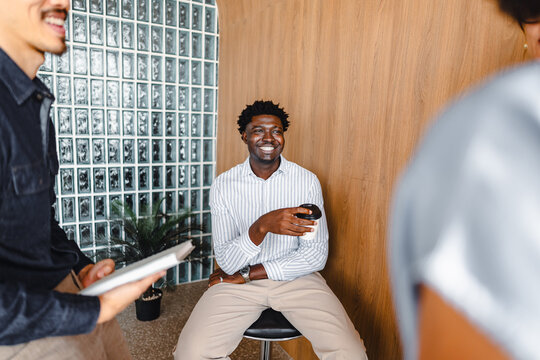 Smiling Man Sitting With Coffee in Modern Office Space