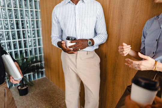 People Talk in an Office Space While Holding Coffee Cups