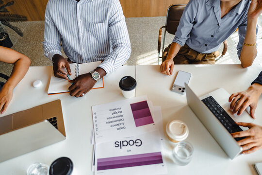 Team Members Working at a Table With Laptops and Notebooks