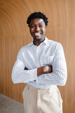Smiling Man Standing With Arms Crossed in Modern Indoor Space