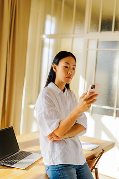 Woman using mobile phone in a sunlit room