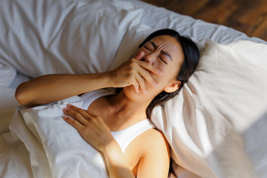 Woman yawning in bed feeling sleepy and tired