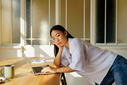 Woman feeling unmotivated working from home on laptop during day