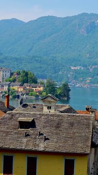 San Giulio Island on Lake Orta, Piedmont, Italy. Aerial 4K vertical  video footage with panoramic view featuring the historic basilica and picturesque lakeside scenery surrounded by Alpine landscapes