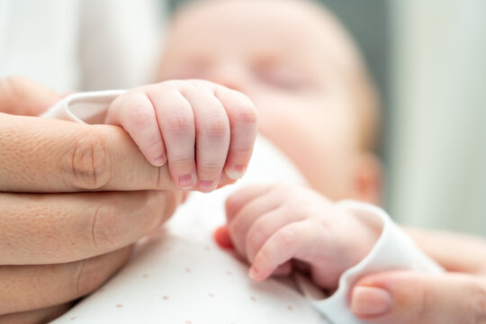 Mother's hand cradled by baby's tiny fingers. Concept of unconditional love from first touch