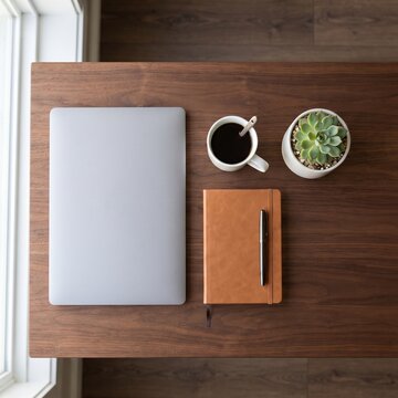 Minimalist workspace top view, laptop and leather notebook on wooden desk. Professional home office setup with coffee and succulent plant.