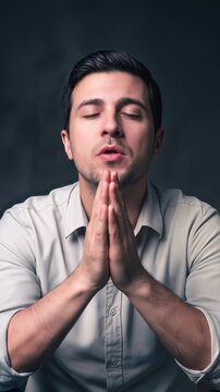 Spiritual person seeking guidance or meditating in a dark studio setting. Mental health and mindfulness concept. Vertical video with tilting camera movement.