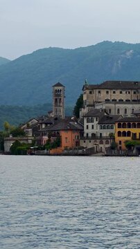 San Giulio Island on Lake Orta, Piedmont, Italy. 4K vertical video footage from boat featuring the historic basilica and picturesque lakeside scenery surrounded by Alpine landscapes