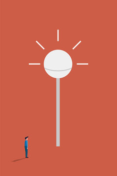 Businessman looking up at a giant glowing light bulb symbol contemplating creative business solutions and strategic future ideas