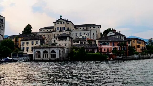 San Giulio Island on Lake Orta, Piedmont, Italy. 4K video footage from boat featuring the historic basilica and picturesque lakeside scenery surrounded by Alpine landscapes
