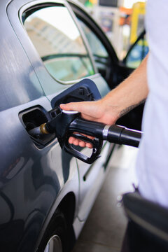 Person filling car with fuel at a gas station, demonstrating the daily routine of refueling for transportation, energy consumption, and vehicle maintenance