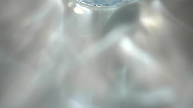 Glass rim casts soft blue reflections and caustic light patterns across a dark surface. Concept abstract optics for ads, websites, banners, magazines and presentations.