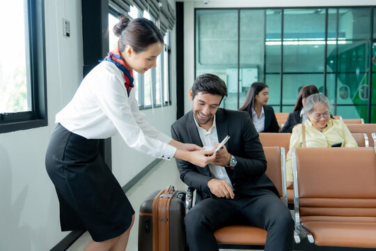 A business traveler receives travel documents from a professional service employee while waiting at an airport with luggage.