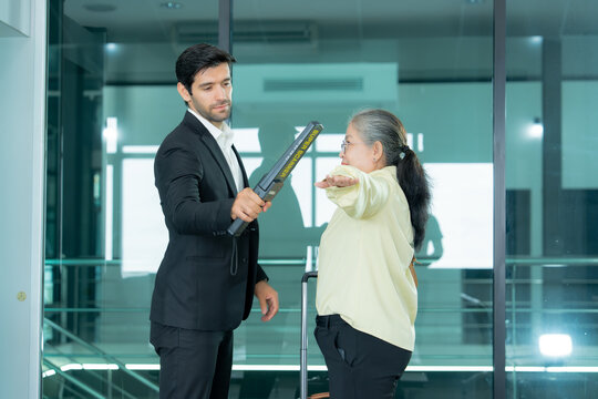 Security personnel screen a traveler with handheld detection equipment in a modern airport setting to support passenger safety and access control. 