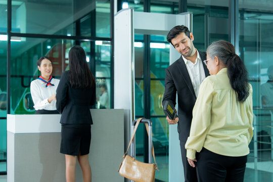 Traveler cooperates with airport personnel during a security inspection near the passenger screening area with luggage ready for departure.