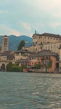 San Giulio Island on Lake Orta, Piedmont, Italy. 4K vertical video footage from boat featuring the historic basilica and picturesque lakeside scenery surrounded by Alpine landscapes