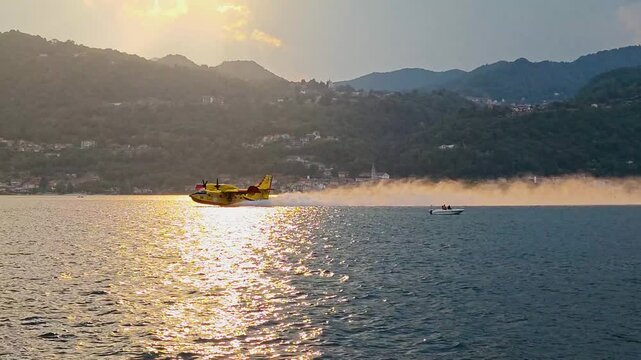 Firefighting Canadair aircraft flying and scooping water from an Italian lake during large forest wildfires, supporting aerial firefighting operations and wildfire suppression in Europe. 4K video