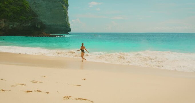 Woman entering turquoise ocean water at Kelingking Beach Bali Nusa Penida