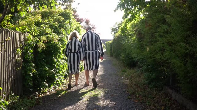 Molle, Sweden A couple in matching black and white striped bathrobes walks down a path to a swimming area in the Oresund Straights. 