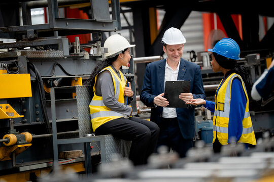 group of professional engineer, worker, technician discuss work, walk in steel metal manufacture factory plant industry. Black African American man and woman wear hard hat check quality machine
