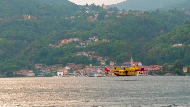 Firefighting Canadair aircraft flying and scooping water from an Italian lake during large forest wildfires, supporting aerial firefighting operations and wildfire suppression in Europe. 4K video