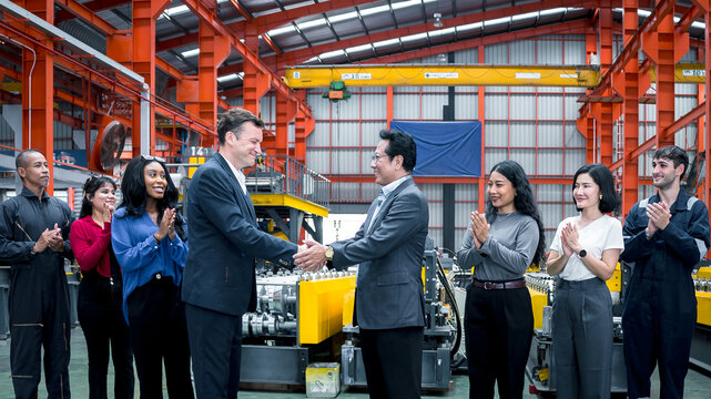 Business partnership in manufacturing. Executives and factory professionals celebrate a successful handshake inside an industrial plant. Partnership, teamwork, leadership, industry, success