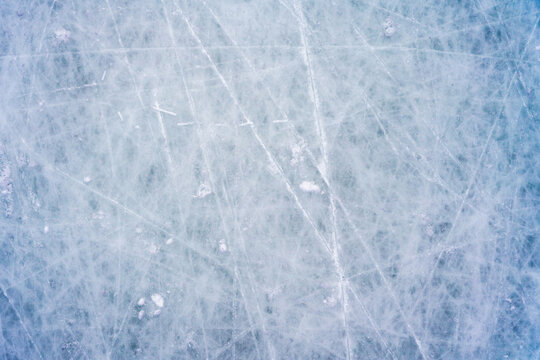 Ice background with marks from skating and hockey, blue texture of rink surface with scratches
