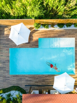 Man Swimming Solo in Luxury Pool Viewed from Above. Concept of relaxation and high-end leisure in a stylish setting