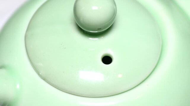 A close-up view of a green teapot on a table. Rotating in a circle