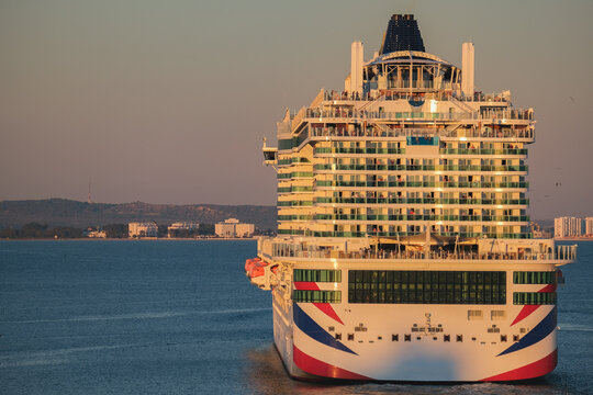 Massive gigantic modern cruiseship cruise ship liner Iona or Arvia in Cadiz, Spain during summer Mediterranean cruising with harbor and container port infrastructure