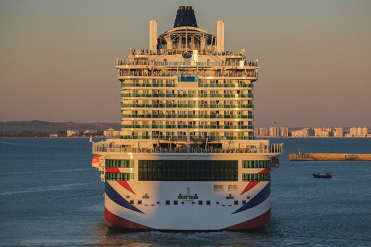 Massive gigantic modern cruiseship cruise ship liner Iona or Arvia in Cadiz, Spain during summer Mediterranean cruising with harbor and container port infrastructure