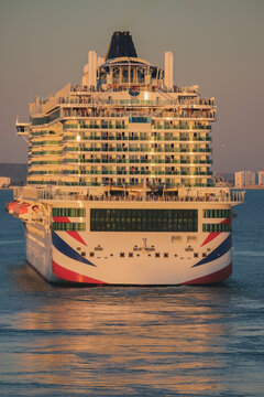 Massive gigantic modern cruiseship cruise ship liner Iona or Arvia in Cadiz, Spain during summer Mediterranean cruising with harbor and container port infrastructure