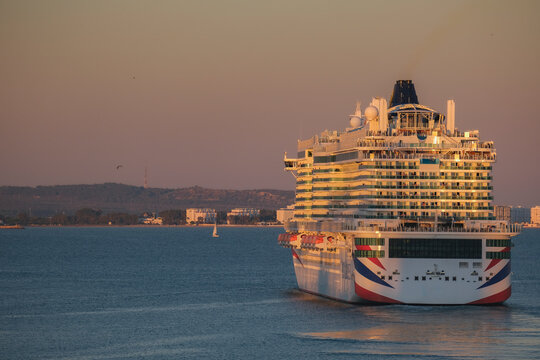 Massive gigantic modern cruiseship cruise ship liner Iona or Arvia in Cadiz, Spain during summer Mediterranean cruising with harbor and container port infrastructure