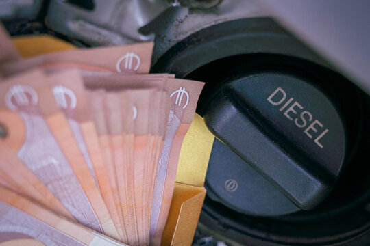 Euro banknotes next to a diesel fuel cap representing rising fuel prices, transportation costs and household expenses