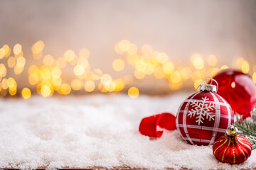 Naklejka premium A Christmas background featuring red baubles with golden glitter stripes, a star, and ribbon framing wide snowy ground, softly lit by warm twinkling lights with generous copy space.