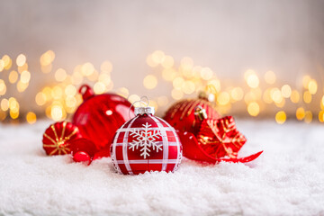 Naklejka premium A Christmas background featuring red baubles with golden glitter stripes, a star, and ribbon framing wide snowy ground, softly lit by warm twinkling lights with generous copy space.