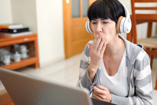 Woman pauses work with yawn. Casual moment of woman yawning during remote work session