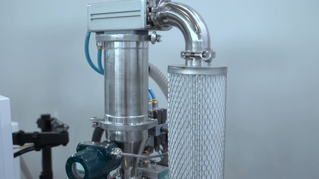 industrial equipment observed in a laboratory or industrial setting with metallic cylinders, pipelines, and valves from a side view. neutral, technical mood with silver and black colors.