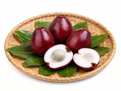 Fresh pomerac fruits and halves with green leaves on a woven bamboo tray
